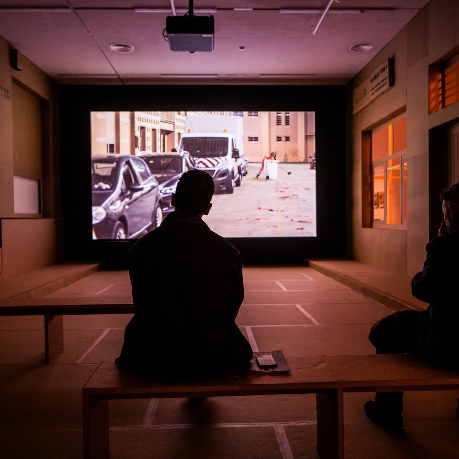 Twee personen kijken naar een film die afgespeeld wordt tijdens de expo Een onzichtbare stad van Thomas Verstraeten